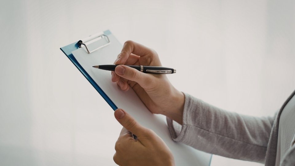 What to Expect in Rehab a woman writes on a clipboard that represents the intake assessment process.