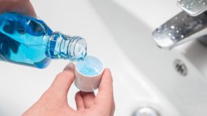 Can You Get Drunk from Alcohol in Mouthwash hero image of a woman pouring mouthwash.