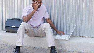 FMLA and Rehab hero image of a man on a computer sitting on a curb.