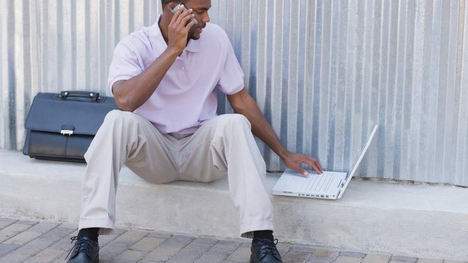 FMLA and Rehab hero image of a man on a computer sitting on a curb.