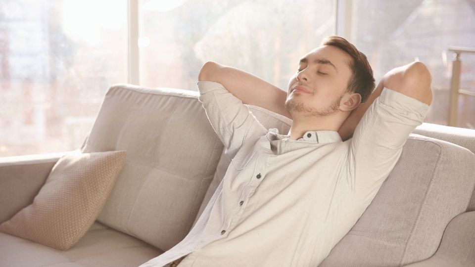 A man practicing HALT rests on couch